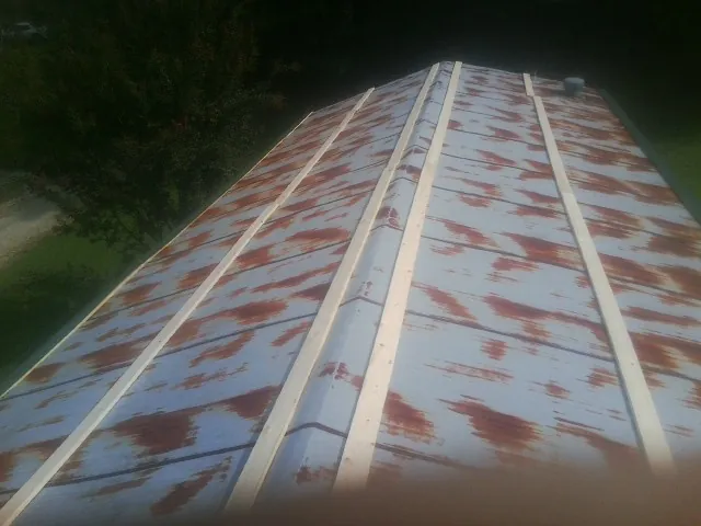 Rusted metal roof panels with new wood purlins before replacement — Storm Damage Roof Repair in Inwood by Roofing Brothers