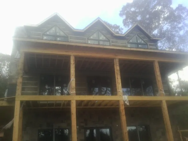 Dormers and porch framing on a large log home under construction — Roof Coating work by our crew in Inwood
