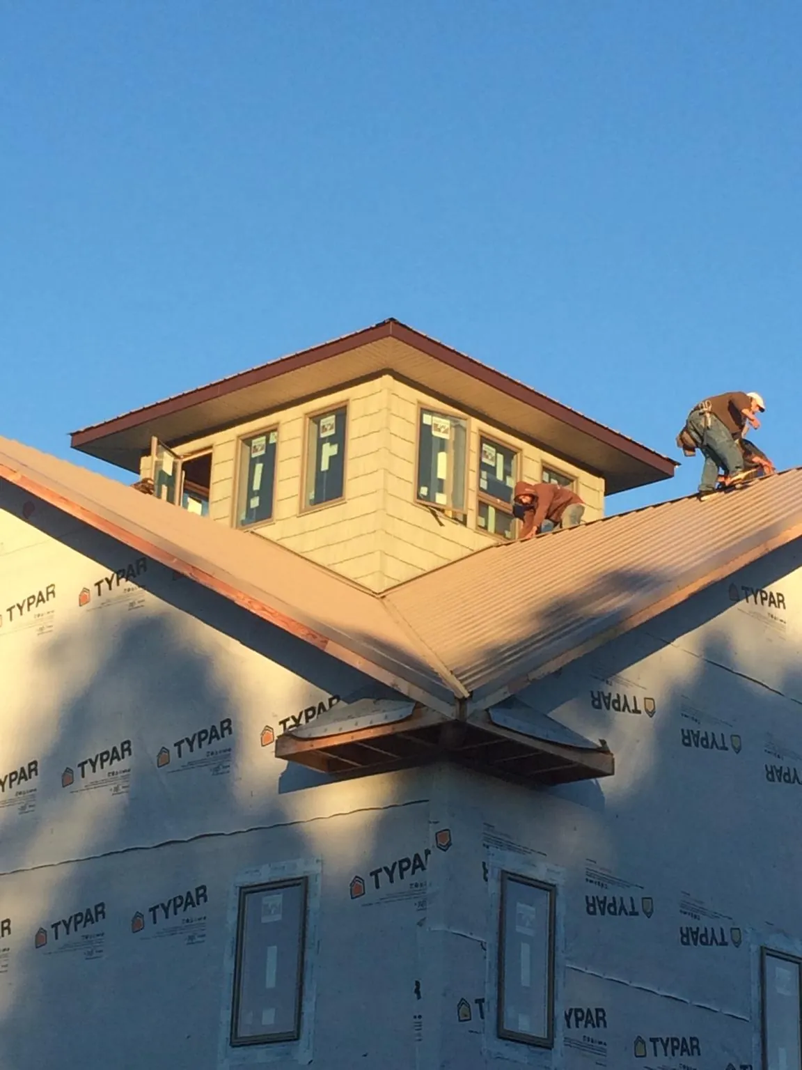Roofers working around a rooftop cupola on a new metal roof at sunset — Roof Waterproofing in Inwood by Roofing Brothers